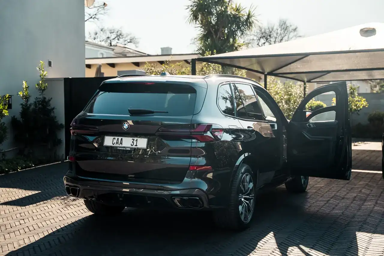 The BMW X5 parked under a carport with the rear door open